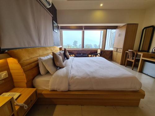 德拉敦Hotel Rajpur Heights的一间卧室设有一张大床和大窗户