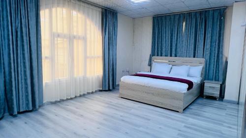 塞拉莱Evan إيفان的一间卧室配有一张带蓝色窗帘的床和一扇窗户