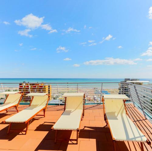 里米尼金色翅膀酒店的俯瞰大海的阳台的一排椅子