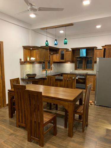 贾夫纳Chety Villa的厨房配有木制橱柜和木桌及椅子