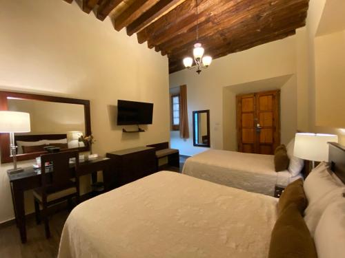 萨卡特卡斯Hotel Casa Faroles Centro Histórico的一间卧室配有两张床、一张桌子和一面镜子