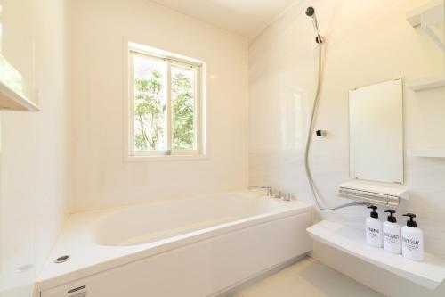 Hirakuboレジーナ石垣　ログテリアⅠ的白色的浴室设有浴缸和水槽。
