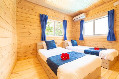 Hirakuboレジーナ石垣　ログテリアⅠ的配有木墙和蓝色窗帘的客房内的两张床