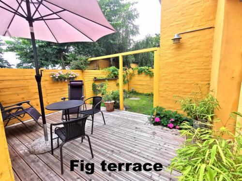 伦讷The FIG Studio - "Den Gule Svane" Guest House - near Rønne & Beach的庭院配有桌椅和遮阳伞。