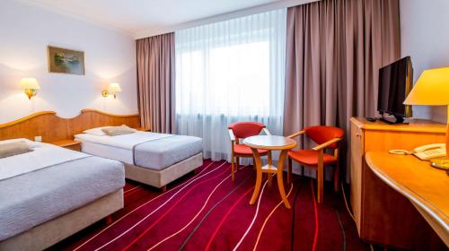 华沙Hotel Felix的酒店客房带两张床和一张桌子以及椅子。
