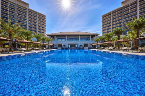 糸满琉球名城海滩度假酒店的一座带椅子的大型游泳池和一座建筑