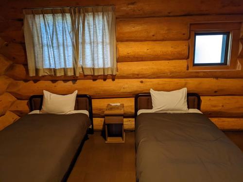 信浓White Tree Log House Madarao Tangram的小木屋内带两张床的房间
