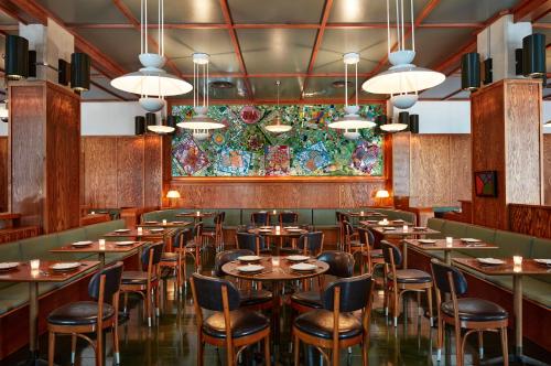 布鲁克林Ace Hotel Brooklyn的餐厅设有桌椅和色彩缤纷的墙壁