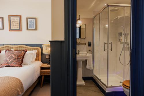 韦斯特勒姆The George & Dragon的一间卧室设有淋浴、一张床和一个水槽。
