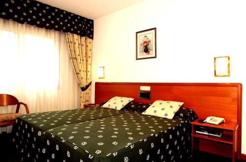 帕德隆斯卡拉酒店的一间卧室配有一张带黑白色床罩的床。