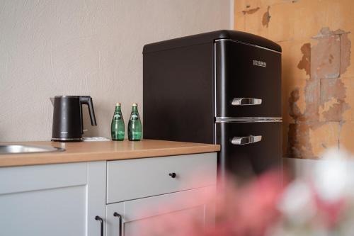 塔尔西Apartaments Nr.33 (Viesu Nr.3)的厨房里的黑色冰箱,在柜台上放有瓶子