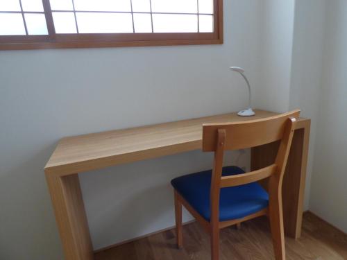 京都Kyoto City - Hotel - Vacation STAY 88891v的一张木桌,窗户下摆放着蓝色椅子