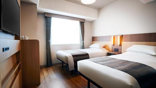 东京Hotel Monte Hermana Tokyo的酒店客房设有两张床和一台平面电视。