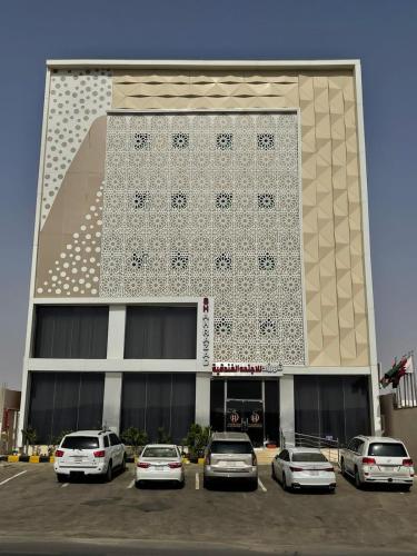 Abū Qa‘arشهرزاد للأجنحة الفندقية的停车场内有车辆的建筑物