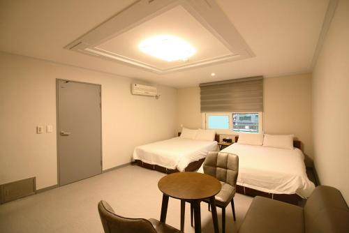 济州市特雷维酒店的酒店客房带两张床和一张桌子以及椅子。