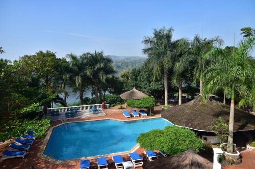 金贾Jinja Nile Resort的一个带椅子和遮阳伞的游泳池以及棕榈树