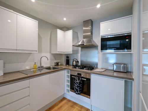 海维康Saffron Court by Wycombe Apartments - Apt 08的厨房配有白色橱柜和炉灶烤箱。