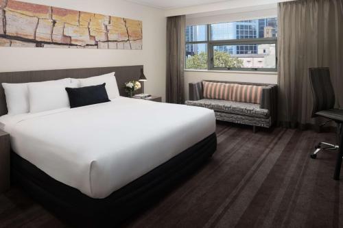 悉尼悉尼雷吉斯世界广场酒店的酒店客房带一张大床和一把椅子