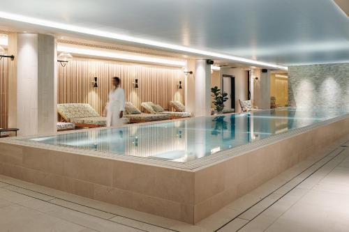 斯德哥尔摩Elite Palace Hotel & Spa的一名妇女在酒店大堂的游泳池周围散步