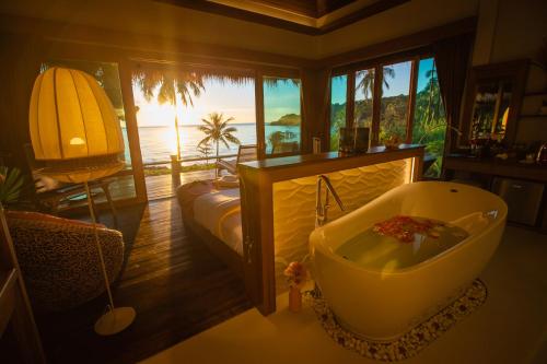 库德岛库德岛天然海滩度假酒店的带浴缸的浴室以及海景床。