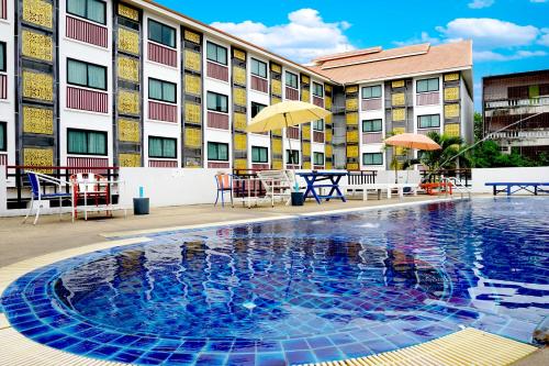 清迈旺布拉帕大酒店的酒店游泳池设有桌椅,酒店大楼