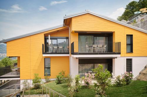 ViganelloReka-Feriendorf Albonago的带阳台的黄色房屋