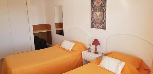 Costa de Santo AndréLagoa Beach & Leisure的小客房内的两张床,配有橙色床单
