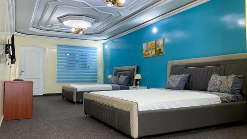 努瓦克肖特Hotel Suites TALHAYA, NOUAKCHOTT的一间卧室设有一张床和蓝色的墙壁