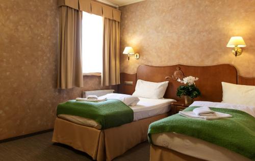 波兹南约瑟夫王子酒店的酒店客房,配有两张带绿毯的床