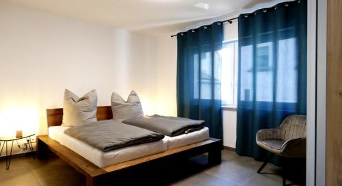 于尔齐希Moselufer Apartments的一间卧室配有一张带蓝色窗帘的床和一把椅子