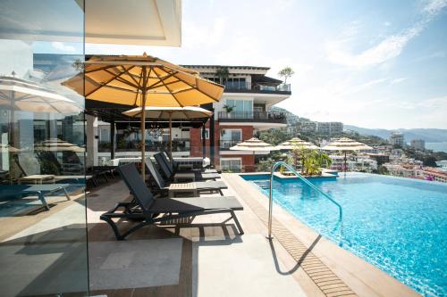 巴亚尔塔港Pinnacle Resorts 179 - Adults Only的一座带椅子和遮阳伞的游泳池位于一座建筑旁边