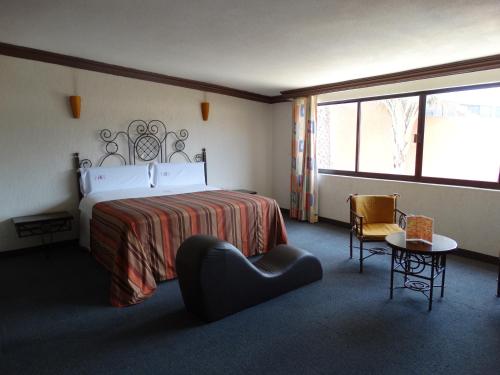 Lerma de VilladaHotel Lerma的配有一张床和一把椅子的酒店客房