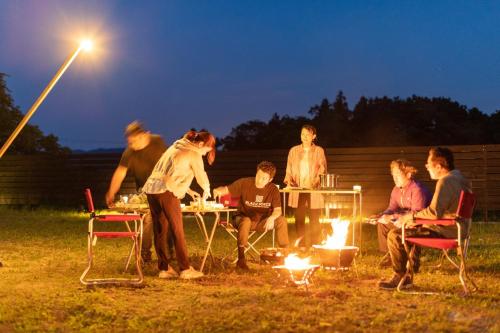 佐渡市guesthouse UZU Sado - Vacation STAY 90684v的一群人围坐在一张桌子旁,围着火
