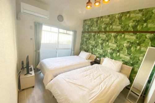 Shimeラ・ポート空港前101的一间卧室设有两张床和绿色的墙壁