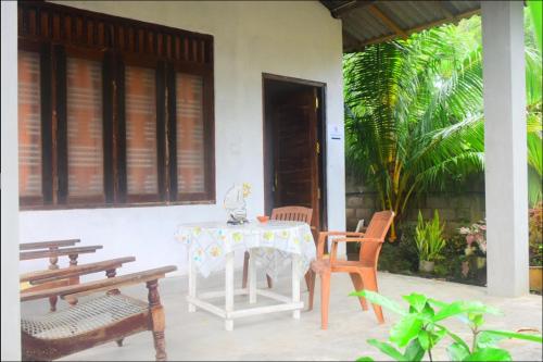 坦加拉Jayanika Residence的门廊上的桌椅,配有桌子和长凳