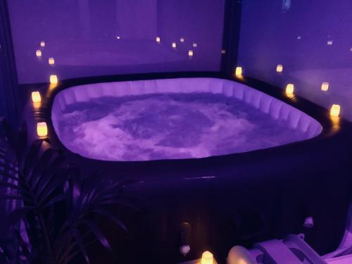 伯明翰Luxury 9ine PENTHOUSE WITH GARDEN & JACUZZI的客房内的紫色浴缸配有灯