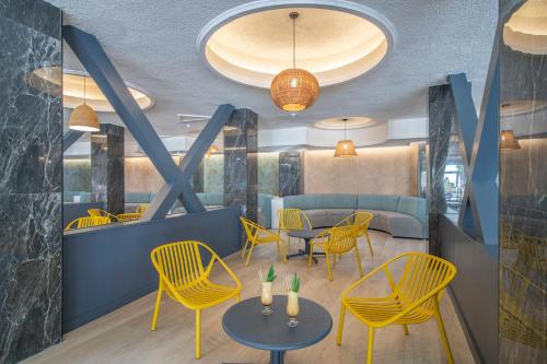 贝尼多姆Hotel Benidorm East by Pierre & Vacances的一间餐厅,房间内设有黄色的椅子和桌子