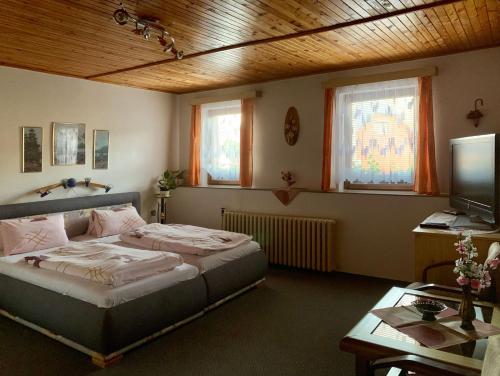 MořinaRestaurace a penzion Na Růžku的一间卧室配有一张床、一张书桌和一台电视