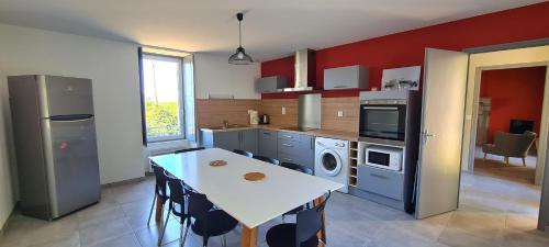 SevremontJoli gîte chez Paulette à 10 min du Puy du Fou的一间带桌子的厨房和一间带红色墙壁的厨房