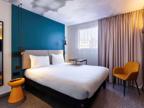 马赛Ibis Marseille Centre Prefecture的酒店客房设有一张大床和一张黄色椅子
