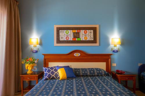 切法卢里瓦德尔索尔酒店的一间卧室设有蓝色墙壁、一张床和两盏灯。