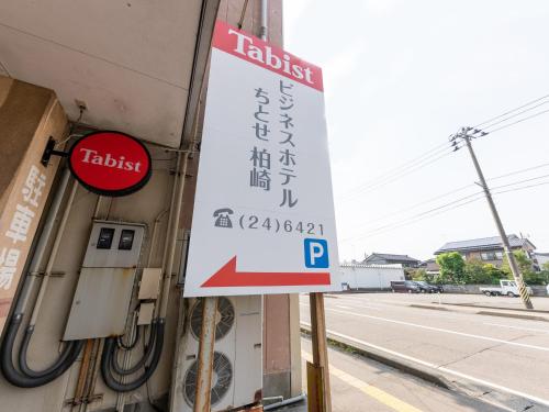 柏崎市Tabist Business Hotel Chitose Kashiwazaki的建筑物边有停车计的标志