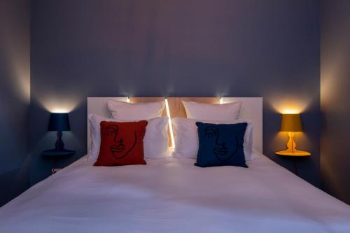勒芒Villa Seyal - avec piscine - jacuzzi - sauna & climatisation的一张带两个红色枕头的床和两盏灯