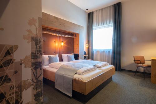 格平根RiKu HOTEL Göppingen的一间卧室配有一张大床和木制床头板