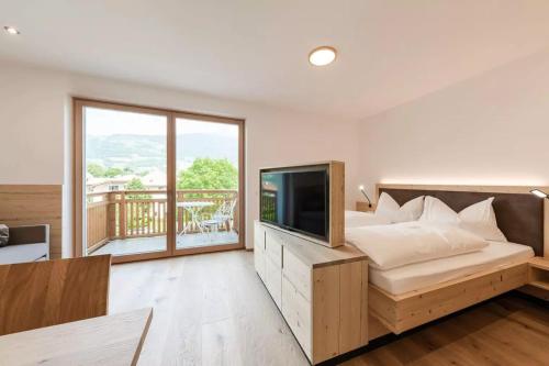丘萨Natur Suite Edelweisshof App Ferdi的一间卧室设有一张床、一台电视和一个阳台。