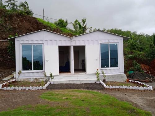 马尔舍吉加特Jandyal Farm House的一座小白色房子,山上设有玻璃门