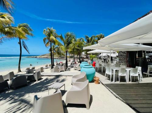 圣弗朗索瓦Villa Nomilou Beach avec Accès direct Plage的海滩上拥有白色的椅子和棕榈树,还有大海
