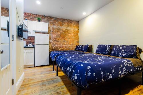 纽约Studios in New York的一间卧室配有一张带蓝色床单和砖墙的床。