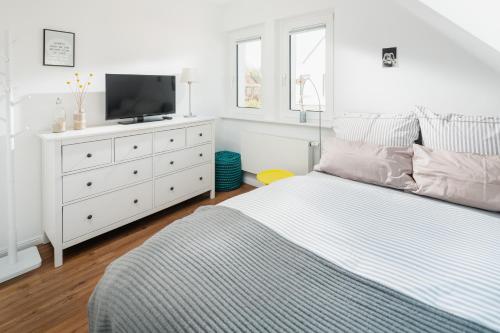 诺德奈Stewohood Norderney的一间卧室配有一张床和一个带电视的梳妆台。