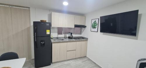 伊瓦格Hermoso Apartamento Entero - Parqueadero - Ibague - Roble的一间带黑色冰箱的厨房和一台电视